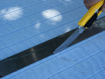 Close-up of hand cutting material with knife