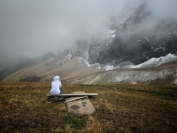 Rear view of man sitting on mountain