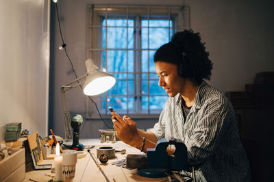 Technician working on equipment while listening music at desk in workshop