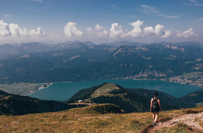 Rear view of woman standing on mountain against sky