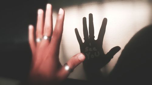 Midsection of person touching shadow on hand