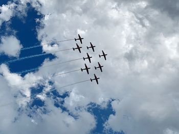 Low angle view of airshow against cloudy sky