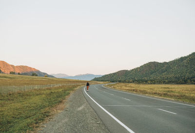 Rear view of woman walking on road against sky