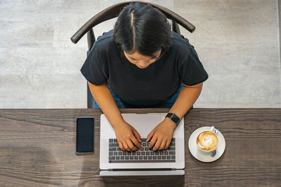Overhead view photo of woman working on laptop in coffeeshop