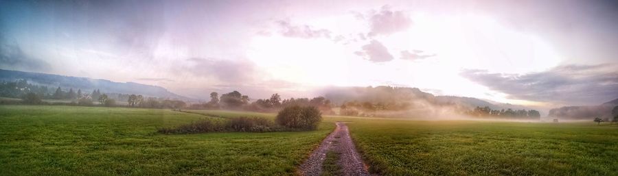 Panoramic view of road amidst field against sky