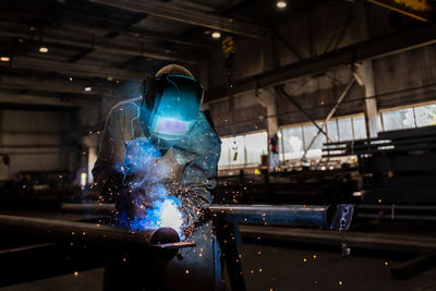 The welder works in the workshop. the moment of welding of metal structures.