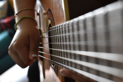 Cropped hand of woman playing guitar at home