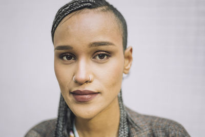 Portrait of confident hipster young woman in front of wall