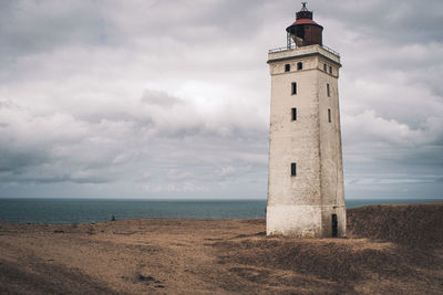 Lighthouse by sea against sky