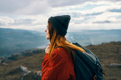 Side view of man looking at mountains against sky