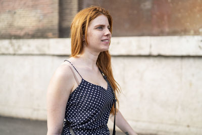 Beautiful young woman standing against wall