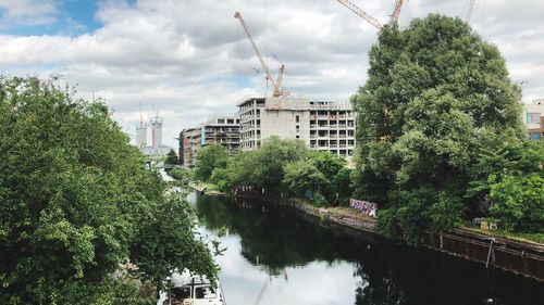 Reflection of trees and buildings in river against sky