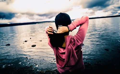 Rear view of woman standing in sea against sky