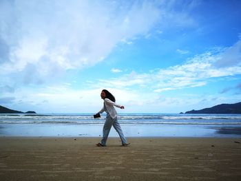 Woman walking at beach against sky