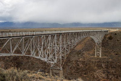 Bridge over gorge with mountain against sky