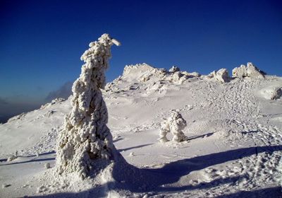 Low angle view of snowcapped mountains against clear blue sky