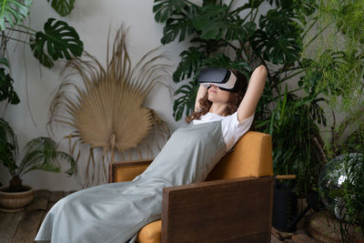 Amazed young woman using vr in home garden, resting in relaxing virtual environment. cyberspace.