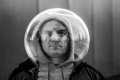 Portrait of man wearing spherical shape glass against wall