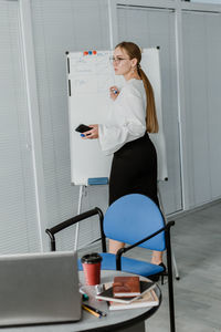Young business woman, speaker coach drawing on white board and having online meeting in office