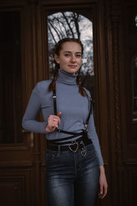 Portrait of young woman standing against entrance