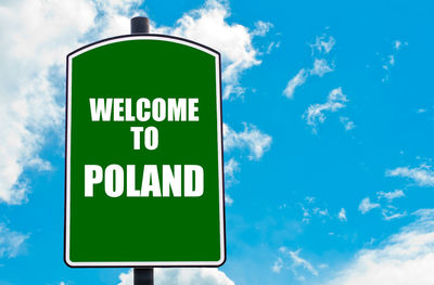 Low angle view of road sign against blue sky