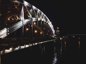 Illuminated bridge over river at night