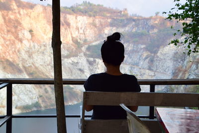 Rear view of woman looking through window