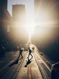 People on railroad tracks in city against sky