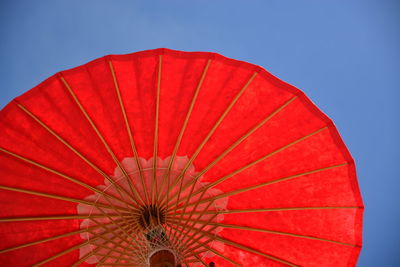 Low angle view of red umbrella against clear blue sky