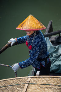 Rear view of man with arms outstretched standing by railing