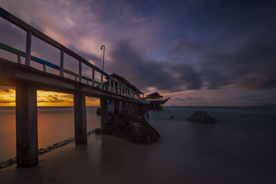Bridge over sea against sky at sunset