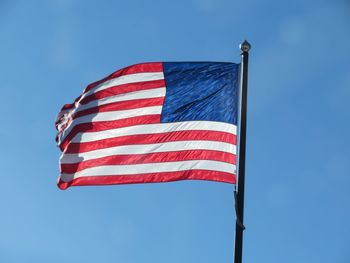 Low angle view of flag against blue sky