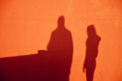 Shadows of man and woman on orange wall