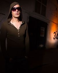 Portrait of serious man wearing sunglasses while standing against wall