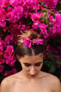 Close-up of young woman against pink flowers