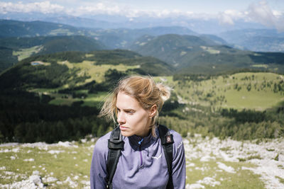 Woman looking away while standing against landscape