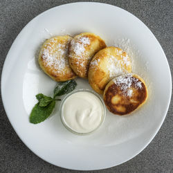 Directly above shot of curd pancakes with sour cream served in plate on table