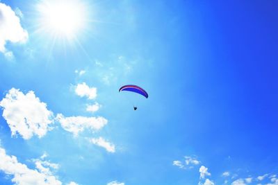 Low angle view of paragliding against blue sky