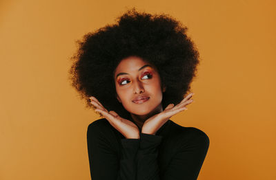 Portrait of beautiful woman with afro hairstyle against yellow background