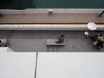 High angle view of people sitting on bench at sidewalk