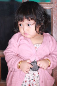 Portrait of cute girl holding pink camera
