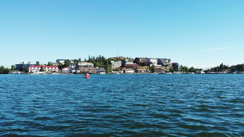 Scenic view of sea by town against clear blue sky