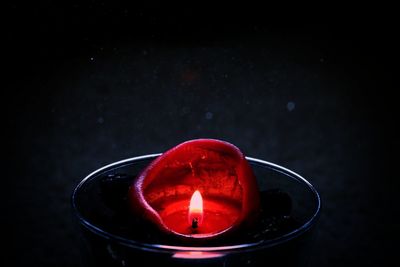 Close-up of illuminated tea light candle against black background