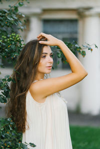 Portrait of a beautiful girl in a summer dress with long hair, who holds her hand in her hair