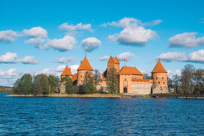 Buildings by river against blue sky