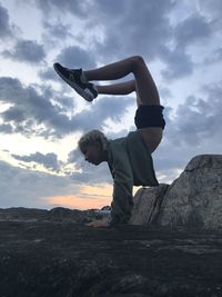 Rear view of man standing on rock against sky