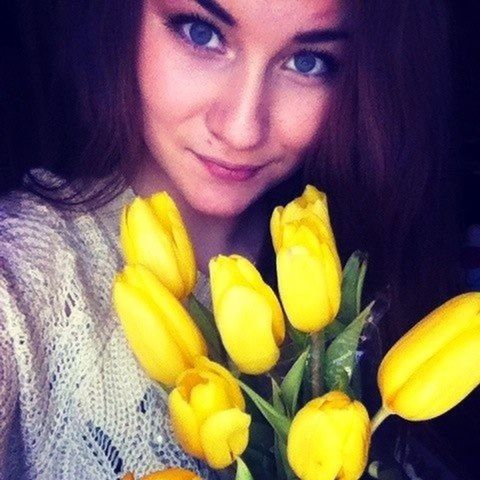 person, indoors, lifestyles, young adult, front view, portrait, young women, looking at camera, headshot, yellow, leisure activity, holding, long hair, casual clothing, close-up, smiling, flower