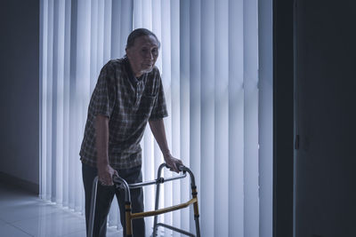 Disabled man walking by blinds with walker 