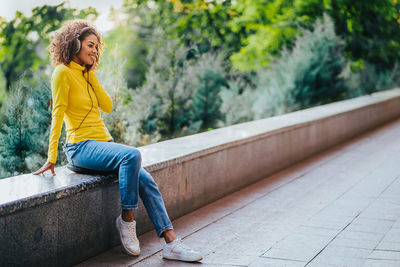 Full length of woman sitting on yellow looking away