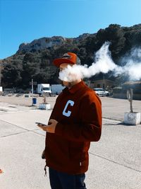 Midsection of man holding hat against sky